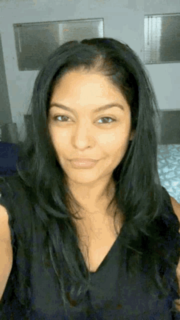 a woman with long black hair is smiling and taking a selfie