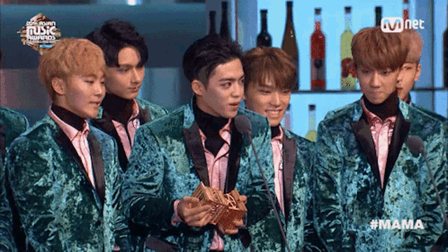 a group of young men standing in front of a mnet sign