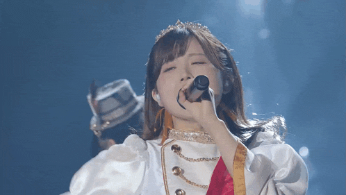 a woman singing into a microphone with a tiara on her head