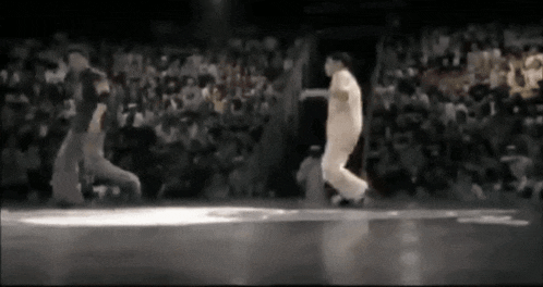 two men are dancing in front of a crowd in a dark room