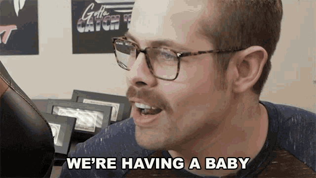 a man wearing glasses and a mustache says we 're having a baby
