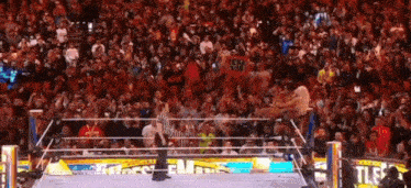 a crowd of people watching a wrestling match with a sign that says ' lm the ' on it