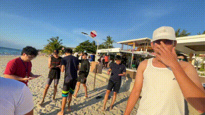 a group of people are standing on a beach and one of them is covering his face .