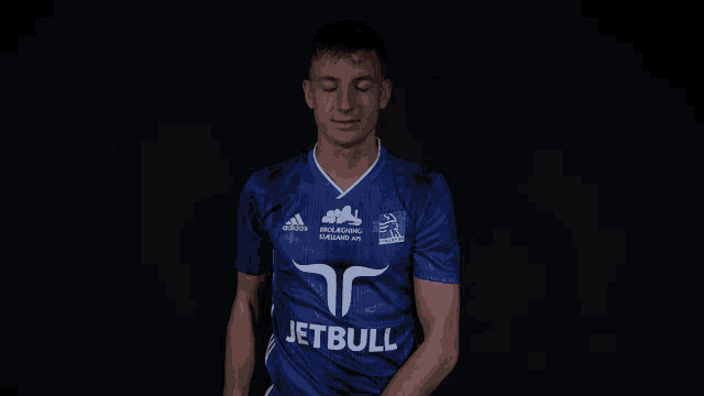 a man wearing a blue jetbull jersey drinks from a glass
