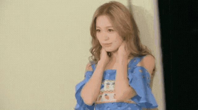 a woman in a blue off the shoulder dress is standing in front of a mirror .