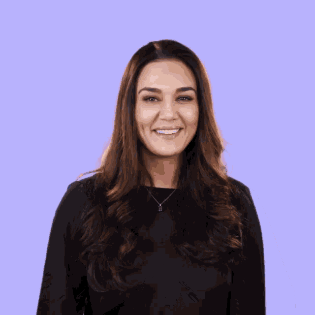 a woman in a black shirt is smiling with her hands together