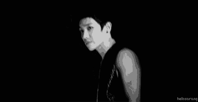 a black and white photo of a young man wearing a black tank top .