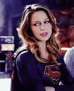 a woman wearing a superman costume looks at the camera