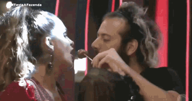 a woman is licking a man 's face with a lollipop