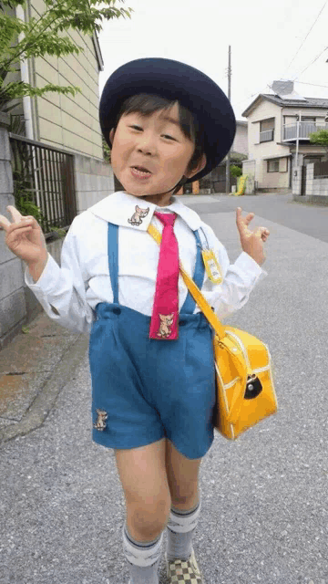 a young boy wearing a hat and tie with a dog embroidered on it