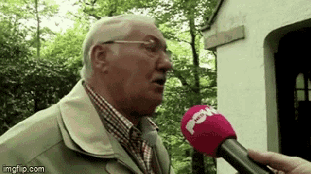 an older man is being interviewed by a person with a red microphone that says nlw