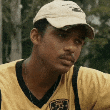 a man wearing a baseball cap and a yellow shirt with the letter u on it