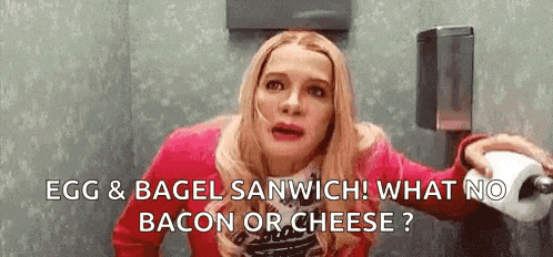a woman is sitting in a bathroom holding a roll of toilet paper and a bagel sandwich .
