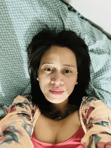 a woman is laying on a bed with a patterned blanket behind her