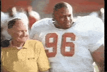 a man in a yellow shirt is standing next to a football player wearing a number 96 jersey