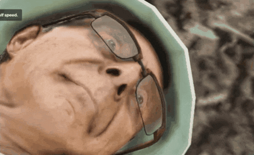 a close up of a man 's face with glasses and a half speed sign in the background