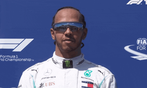 a man wearing sunglasses and a mercedes uniform giving a peace sign