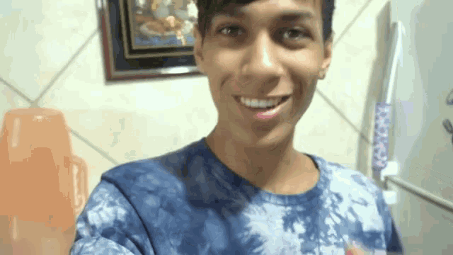 a young man wearing a tie dye shirt is smiling