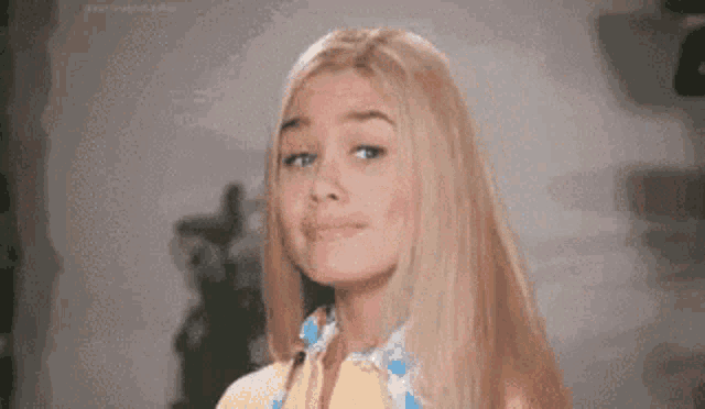 a blonde woman is smiling and looking at the camera .