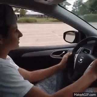 a woman is driving a car in a parking lot while holding the steering wheel .