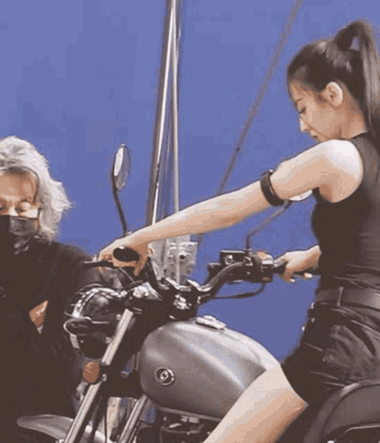 a woman in a black tank top is riding a yamaha motorcycle