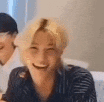 a man with blonde hair is sitting on a couch smiling .