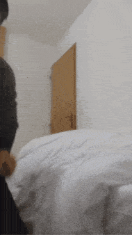 a person is standing next to a bed with white sheets