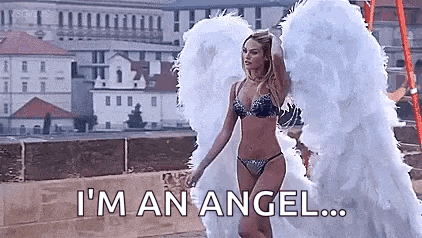 a woman in a bikini and angel wings is standing on a bridge .