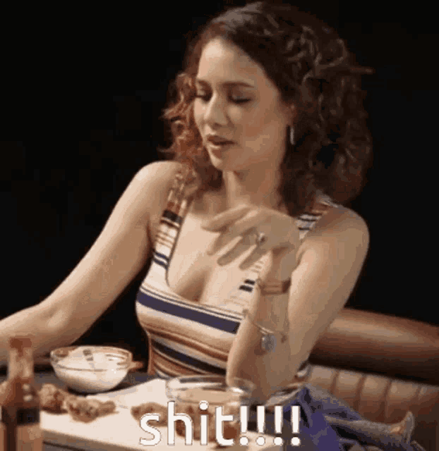 a woman in a striped tank top is sitting at a table with a bowl of food and says shit