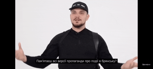 a man wearing a black shirt and a black hat is talking in foreign language