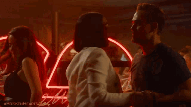 a man and woman are dancing in front of a neon sign
