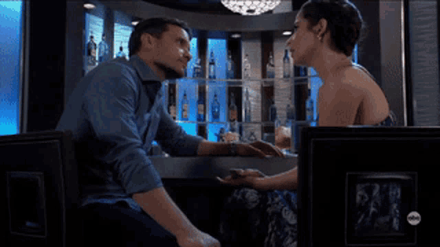 a man and a woman sitting at a bar holding hands