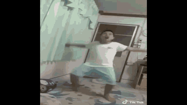 a young man is dancing in a living room .
