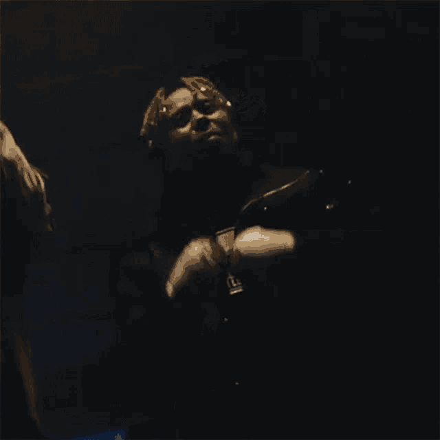 a man in a black jacket is standing in a dark room with a light on his head .
