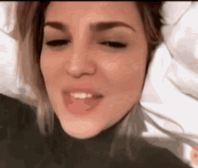 a close up of a woman 's face with her eyes closed and a smile on her face .