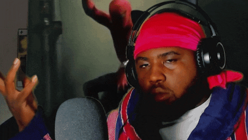 a man wearing headphones and a pink headband has his fist in the air