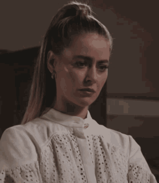 a woman is wearing a white shirt with holes in it and a ponytail