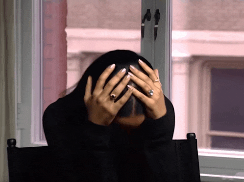 a woman covering her face with her hands while wearing a ring