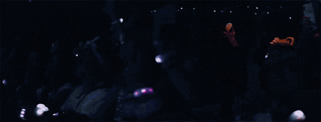 a group of women are dancing on a stage with purple lights behind them .