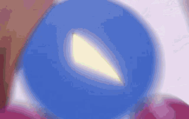 a close up of a clown 's face with a blue ball in his eye and a pink ball in his mouth .
