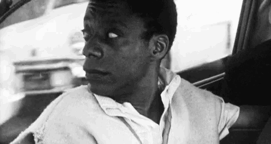 a man is sitting in the back seat of a car looking out the window .