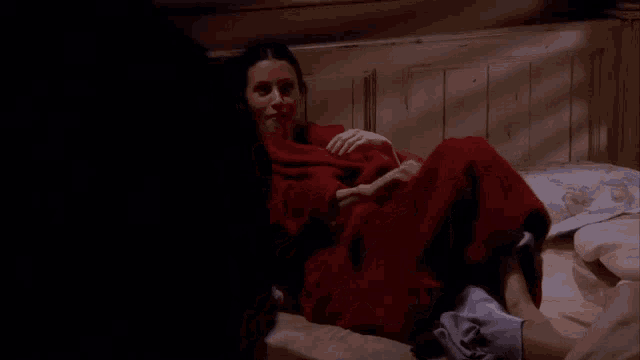 a woman in a red robe is laying on a bed with her legs crossed .