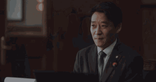 an older man in a suit is sitting in front of a microphone with his eyes closed .