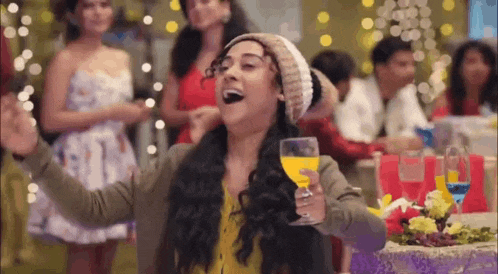 a woman is holding a glass of wine and laughing at a christmas party .