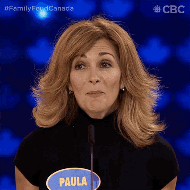 a woman stands in front of a microphone with a sign that says paula