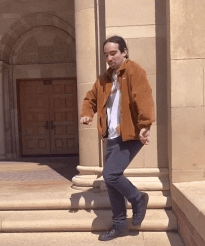 a man in a brown nike jacket stands on a set of stairs