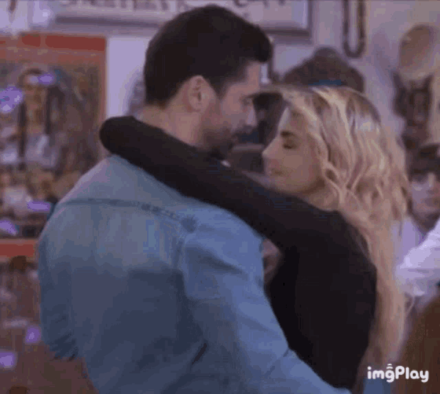a man and a woman are hugging each other while dancing in a room .