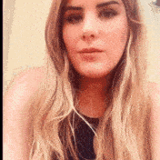 a woman with long blonde hair is wearing headphones and making a funny face .