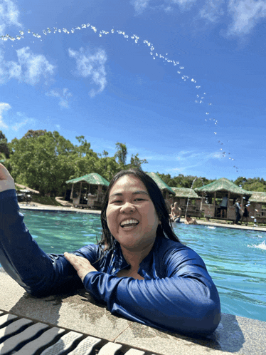 a woman in a blue shirt is splashing water in a pool