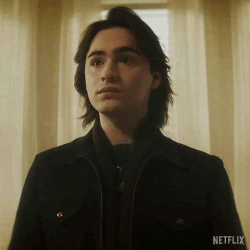a young man standing in front of a window with netflix written on the bottom right